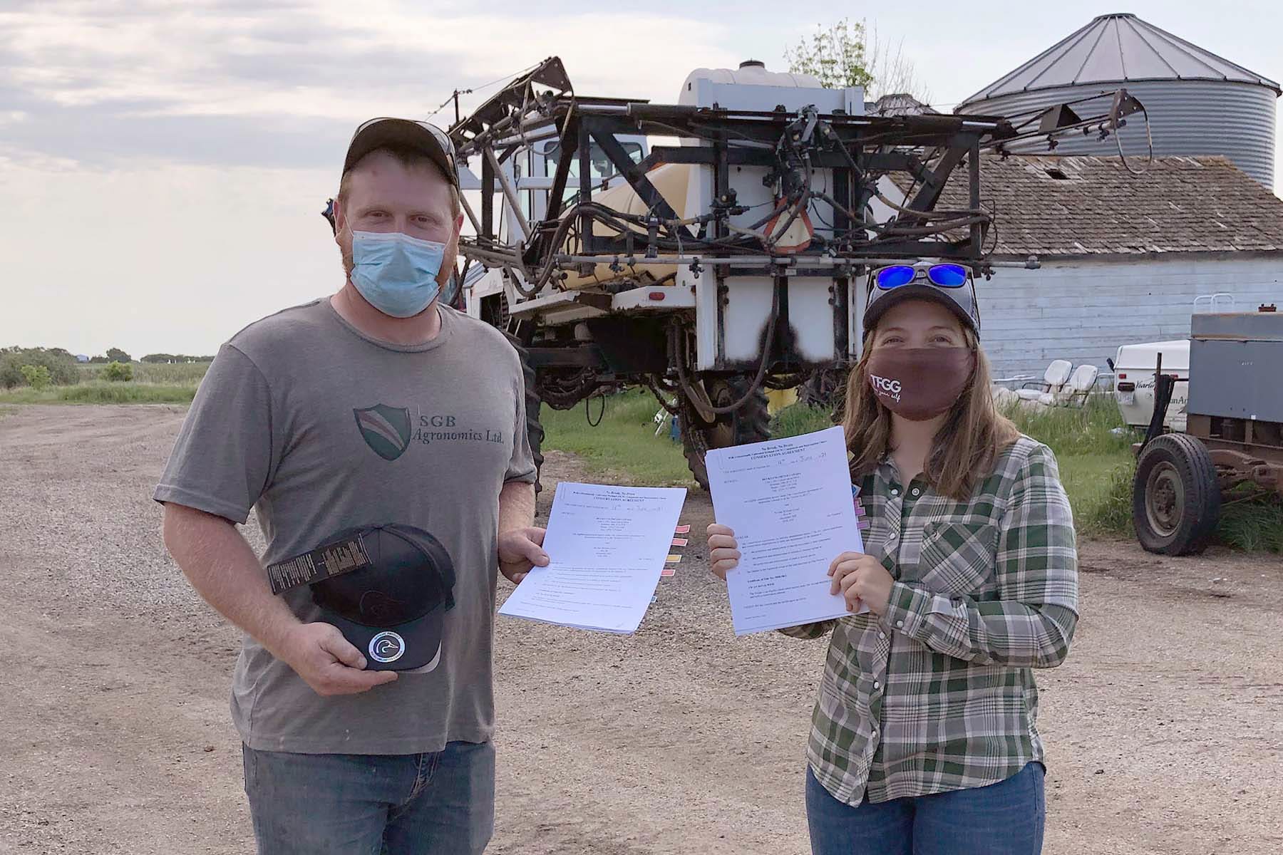 photo shows Alexander-area farmer Bryden Izzard signing a 70 acre conservation agreement in 2021 with Kylie Nielson from DUC