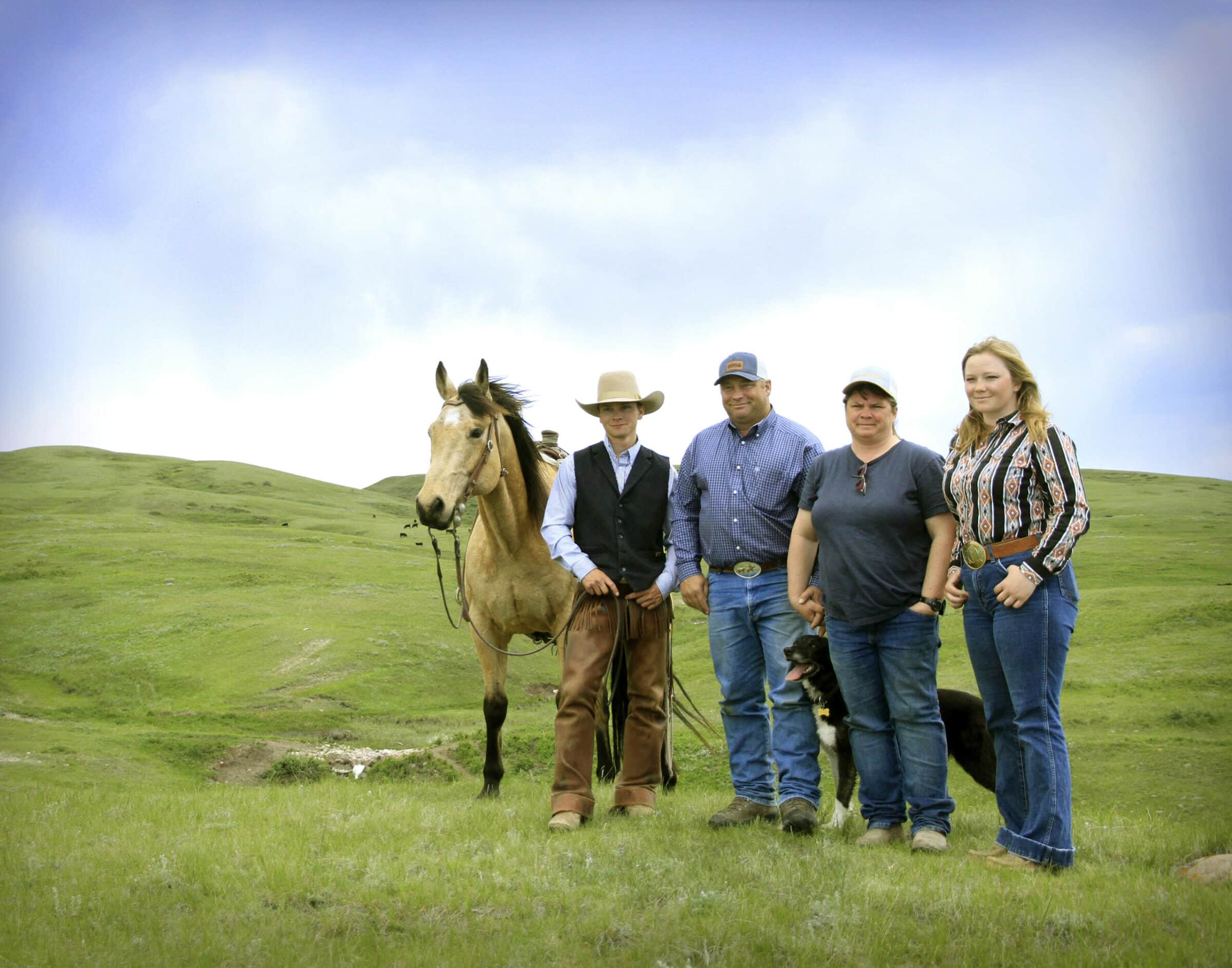 Rob and Audrey Taylor and their two adult children stand on a green grassland range with a horse and a dog