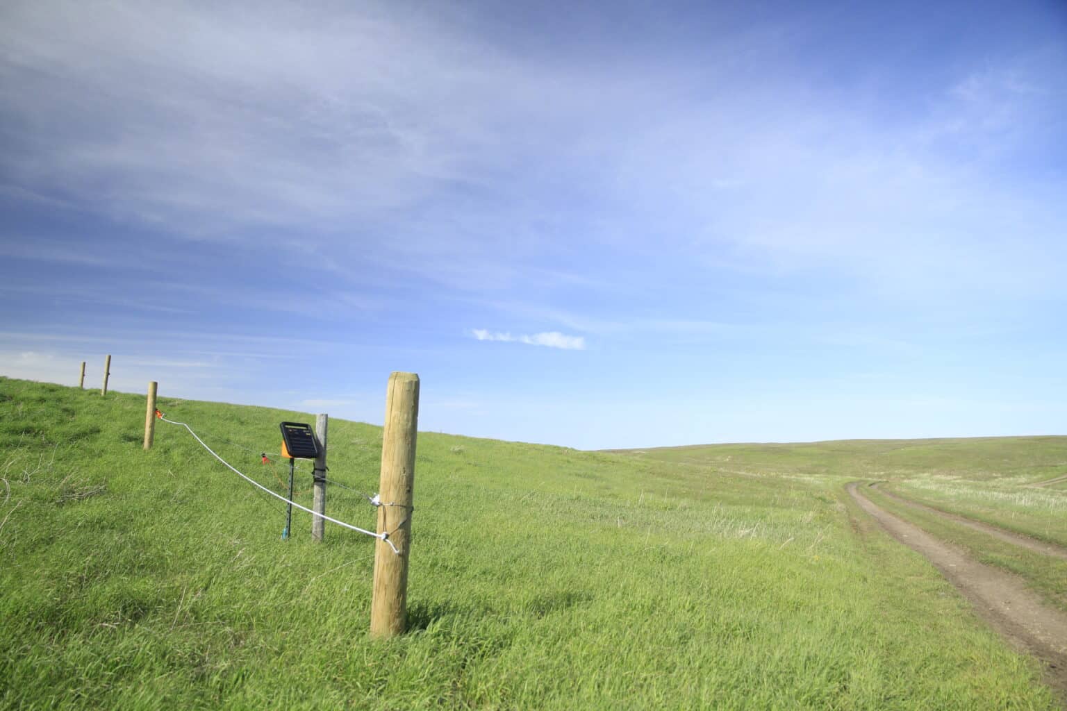 A small solar panel and electric fence in a green pasture